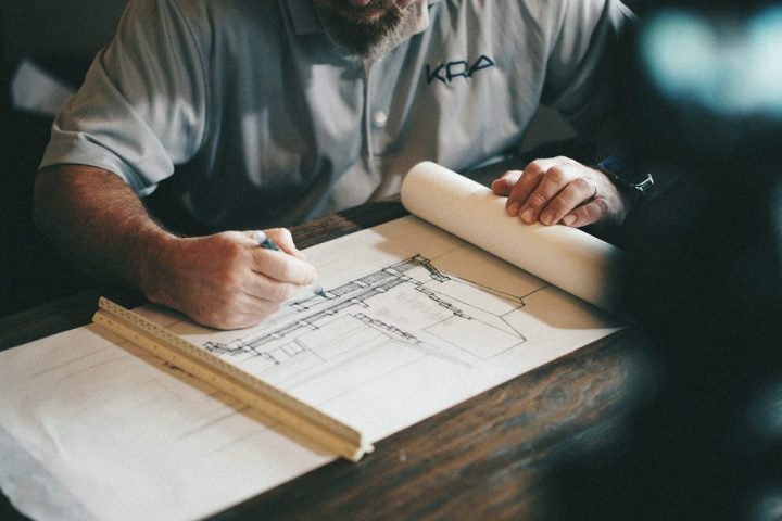 Mâini trasând un plan tehnic cu rigla, la lumină de lucru