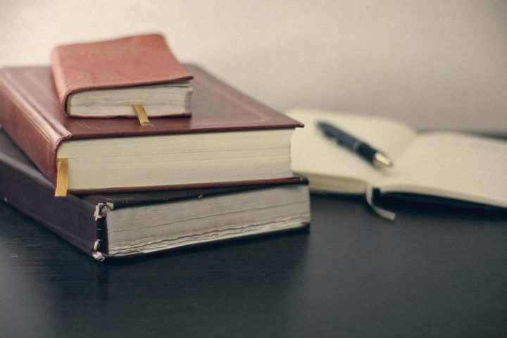 Registre și un stilou pe un birou întunecat